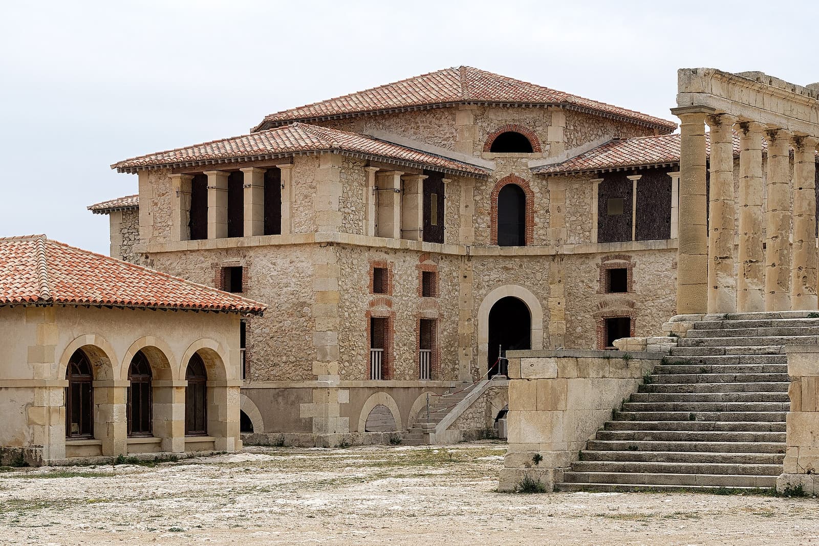 Die Steinfassade und Treppe des Hôpital Caroline auf der Île Ratonneau unter weißem Himmel