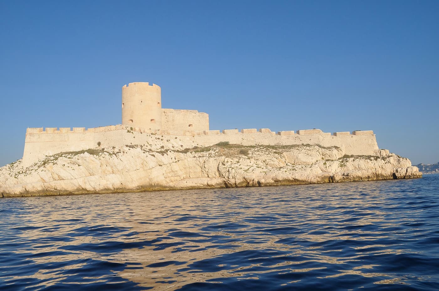 The Château d'If and its lighthouse on the low white rock of the island under a clear sky