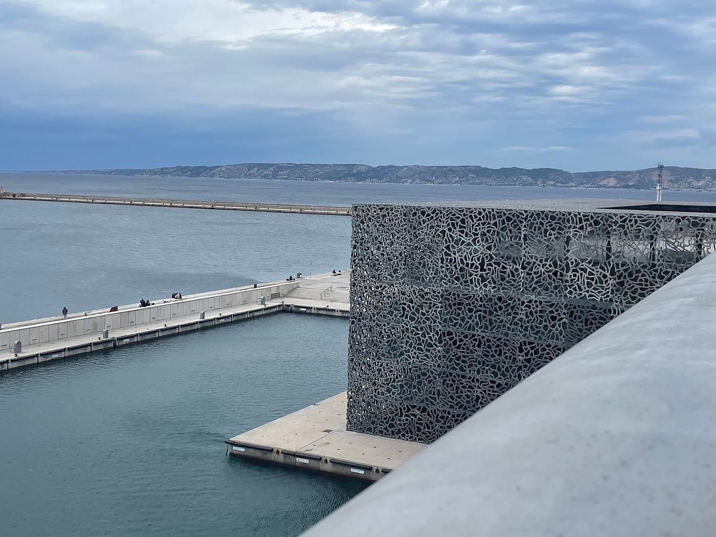 The latticed concrete cube of the MuCEM on the waterfront, with the harbour breakwater beyond